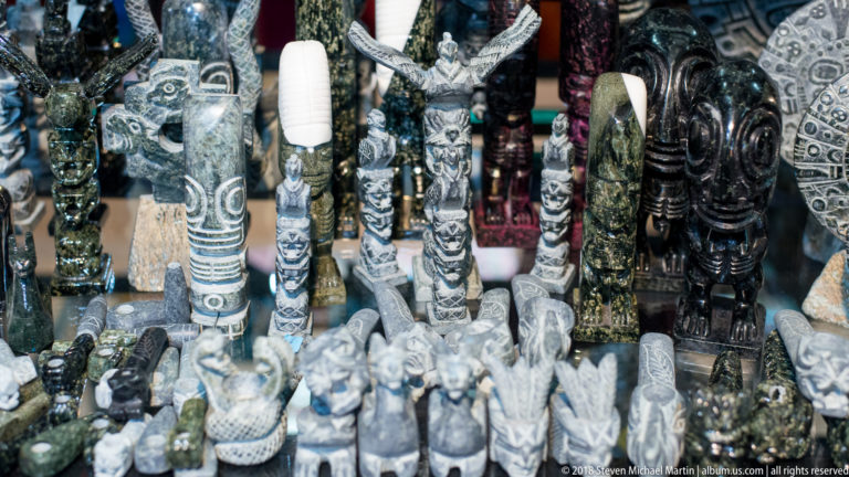 Rows of small carved human and animal figurines displayed closely together in a Cusco artisan shop.