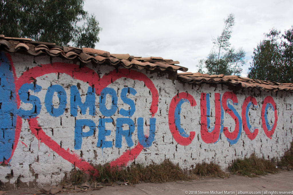 Weathered wall painted with a red heart containing Somos Perú and large red Cusco lettering.