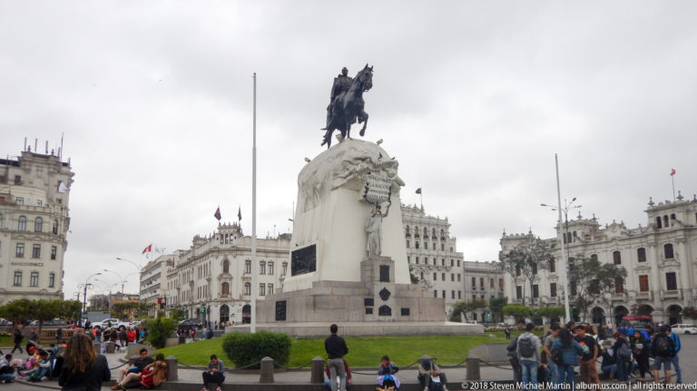 José de San Martín equestrian monument centered in a busy plaza surrounded by ornate historic buildings and pedestrians.