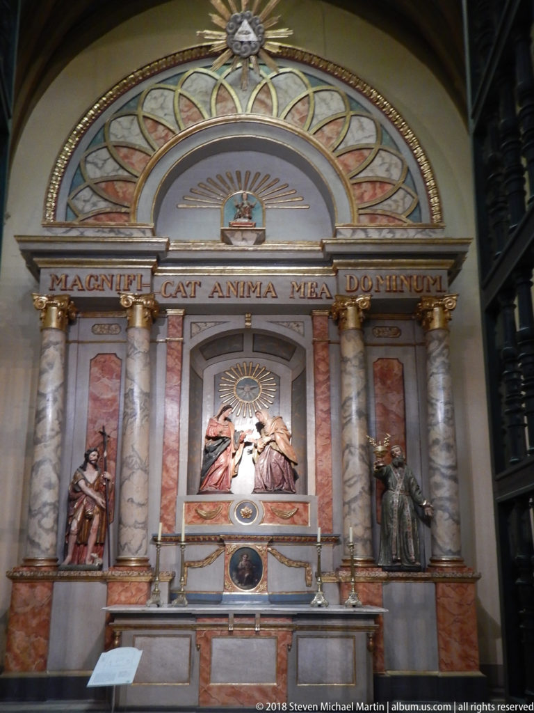 Ornate Marian side altar with marbleized columns, saint figures, radiant sunburst, and Latin inscription above the shrine.