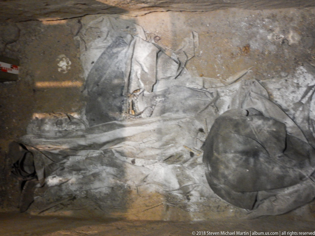 Partially exposed human skeletal remains embedded in compacted earth or masonry within a cathedral burial context.