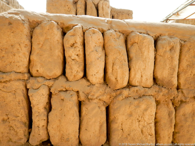 Two close courses of irregular hand-formed adobe blocks set upright and joined with earthen mortar at Huaca Pucllana.