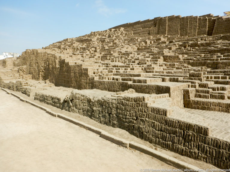 Oblique view of the Great Pyramid at Huaca Pucllana, with stepped adobe terraces rising beside a visitor path.