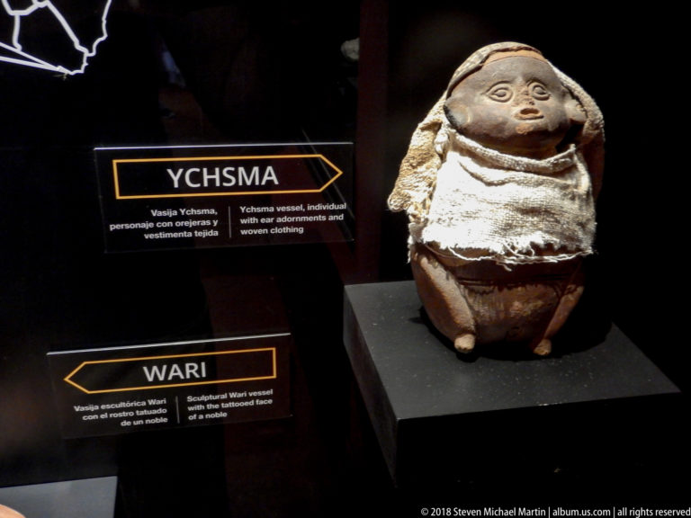 Anthropomorphic ceramic vessel with modeled face and wrapped surface displayed beside Ychsma and Wari interpretive labels.