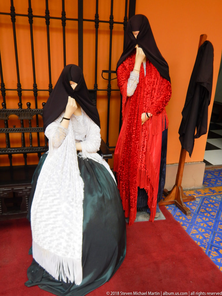 Two mannequins in white-dark and red saya-and-manto costumes with faces largely concealed by dark mantles.