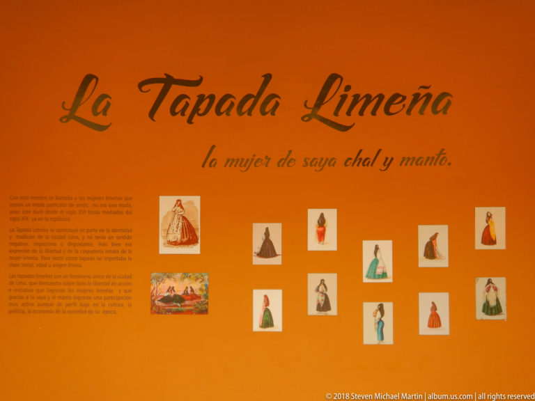 Orange interpretive panel titled La Tapada Limeña with text and small illustrations of women in saya-and-manto dress.