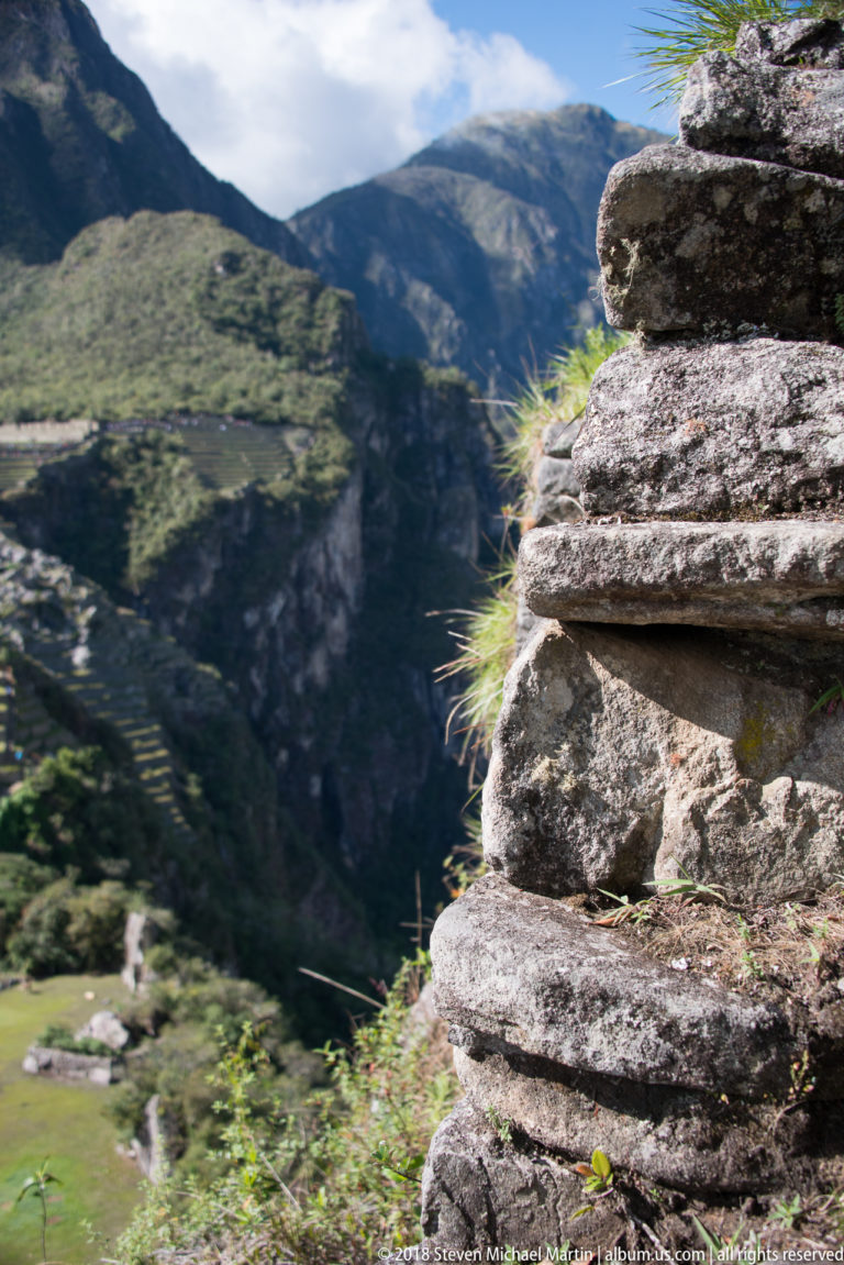 Weathered stacked stone masonry with grass in the joints at a high mountain edge on Huayna Picchu.