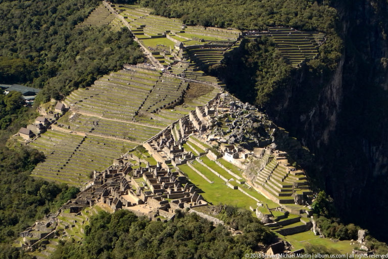 Near-vertical view from Huayna Picchu over Machu Picchu’s terraced fields, stone buildings, and green central spaces.