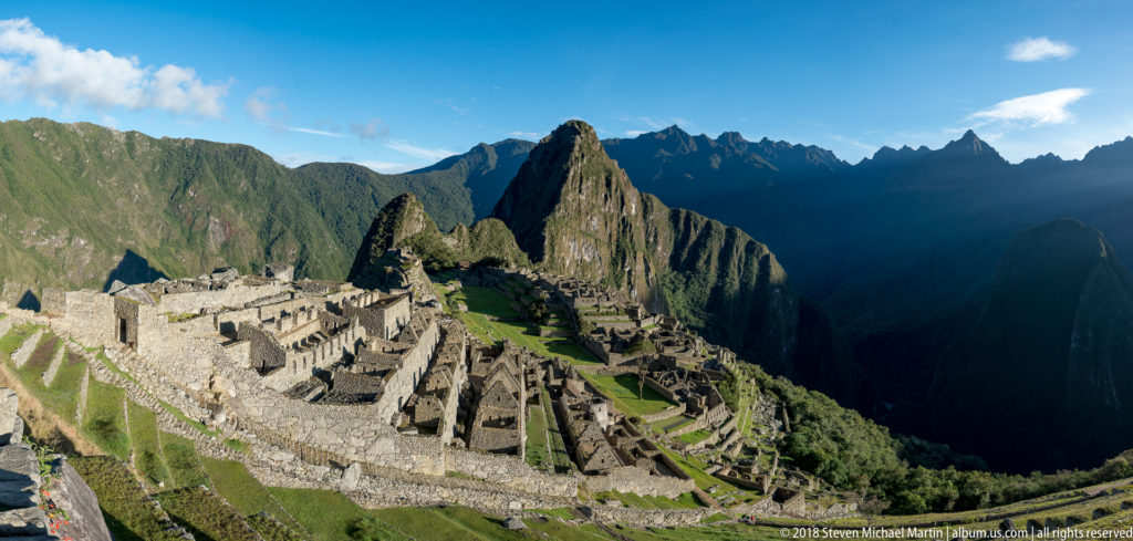 Broad view of Machu Picchu’s stone buildings and terraces with Huayna Picchu rising behind.