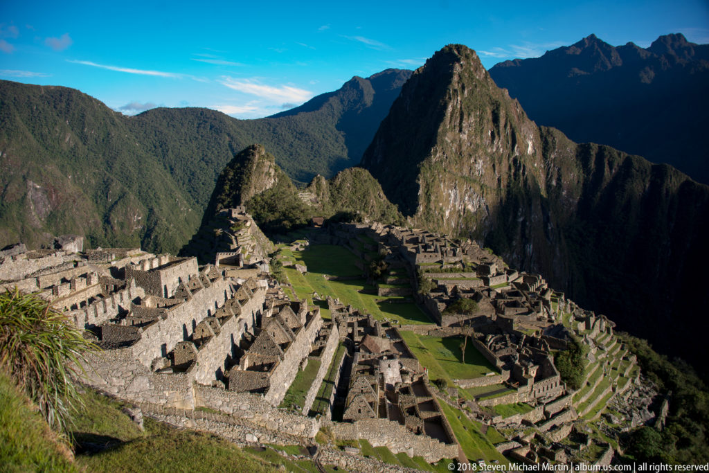 Broad panorama of Machu Picchu’s stone buildings and terraces with Huayna Picchu rising behind.