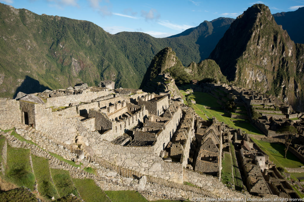 Elevated panorama across Machu Picchu’s stone rooms, lawns, terraces, and Huayna Picchu.