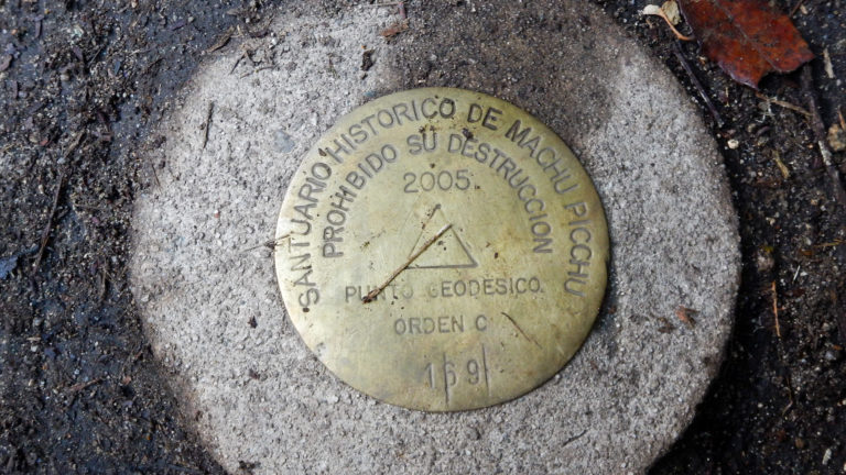 Round brass-colored geodetic marker inscribed for the Santuario Histórico de Machu Picchu and dated 2005.