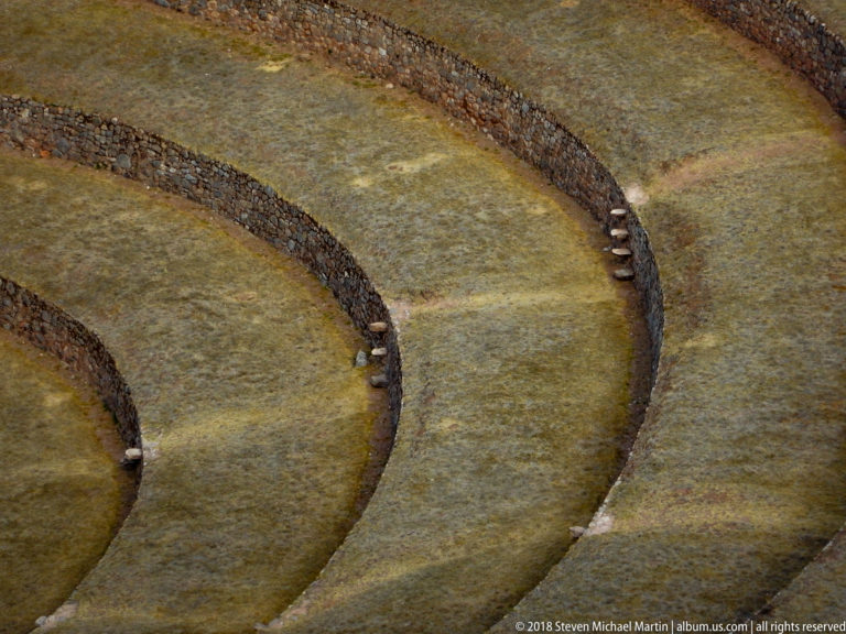 Three curved grassed terraces at Moray with dark retaining walls and small projecting-stone stairways.
