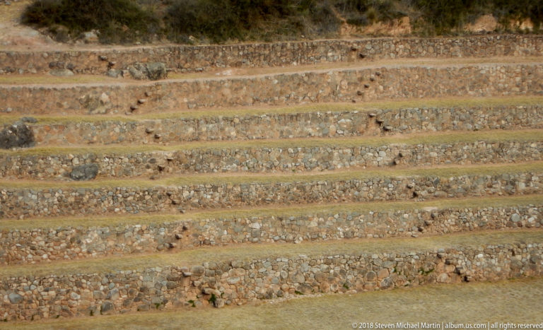 Dense horizontal bands of irregular stone retaining walls and narrow dry grass terrace benches at Moray.