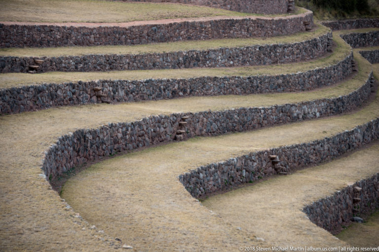Rounded grass-covered terrace ends and dark stone retaining walls at Moray, with a small projecting-stone stair.
