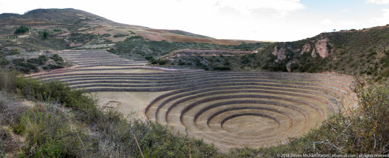 Concentric circular terraces descending into a broad bowl at Moray, with stone retaining walls and additional terraces beyond.