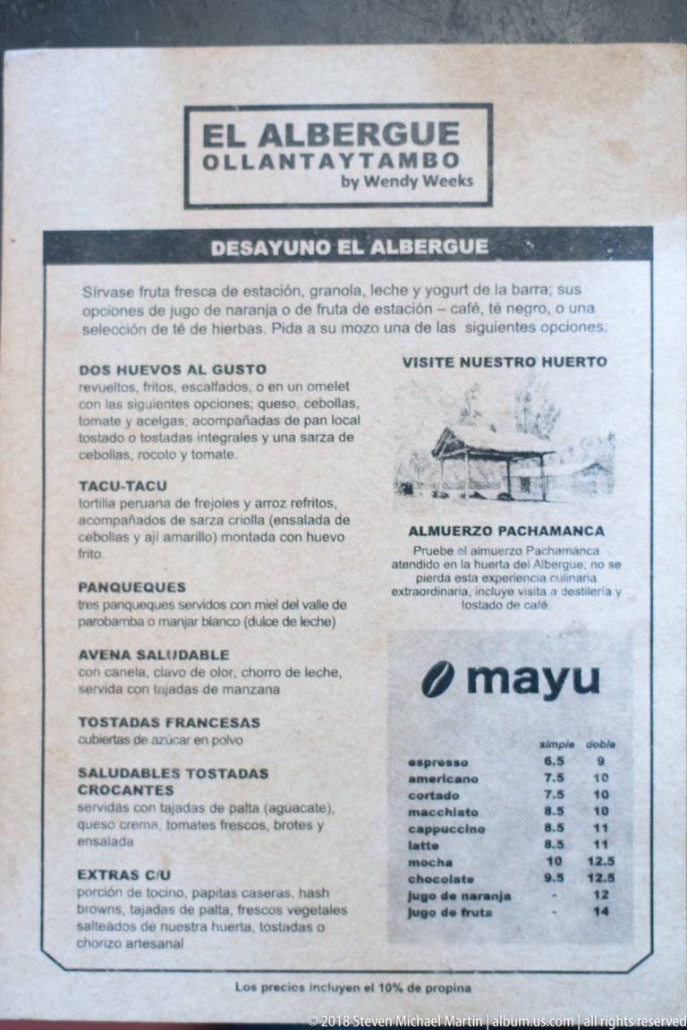 Printed El Albergue Ollantaytambo menu board listing breakfast, lunch, and drink offerings.