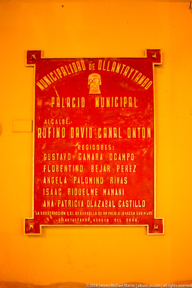 Red municipal plaque reading “Municipalidad de Ollantaytambo” and “Palacio Municipal” with officials’ names.