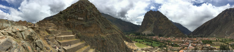 Elevated wide view of Machu Picchu terraces and ruins with Huayna Picchu centered in the distance.