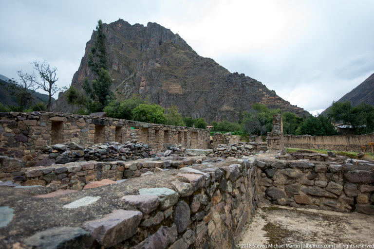 Low stone room foundations and doorways in front of the steep mountain at Ollantaytambo.