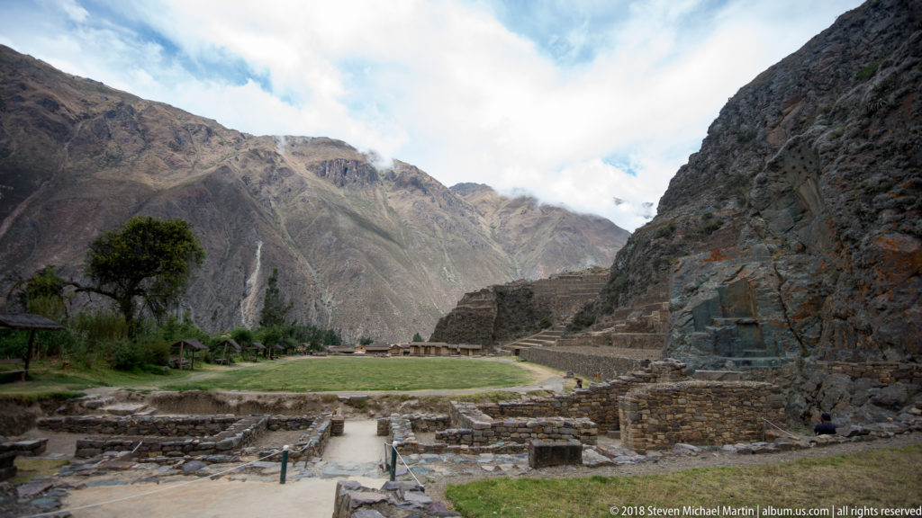 Low stone foundations and walls in front of the terraced Temple Hill at Ollantaytambo.