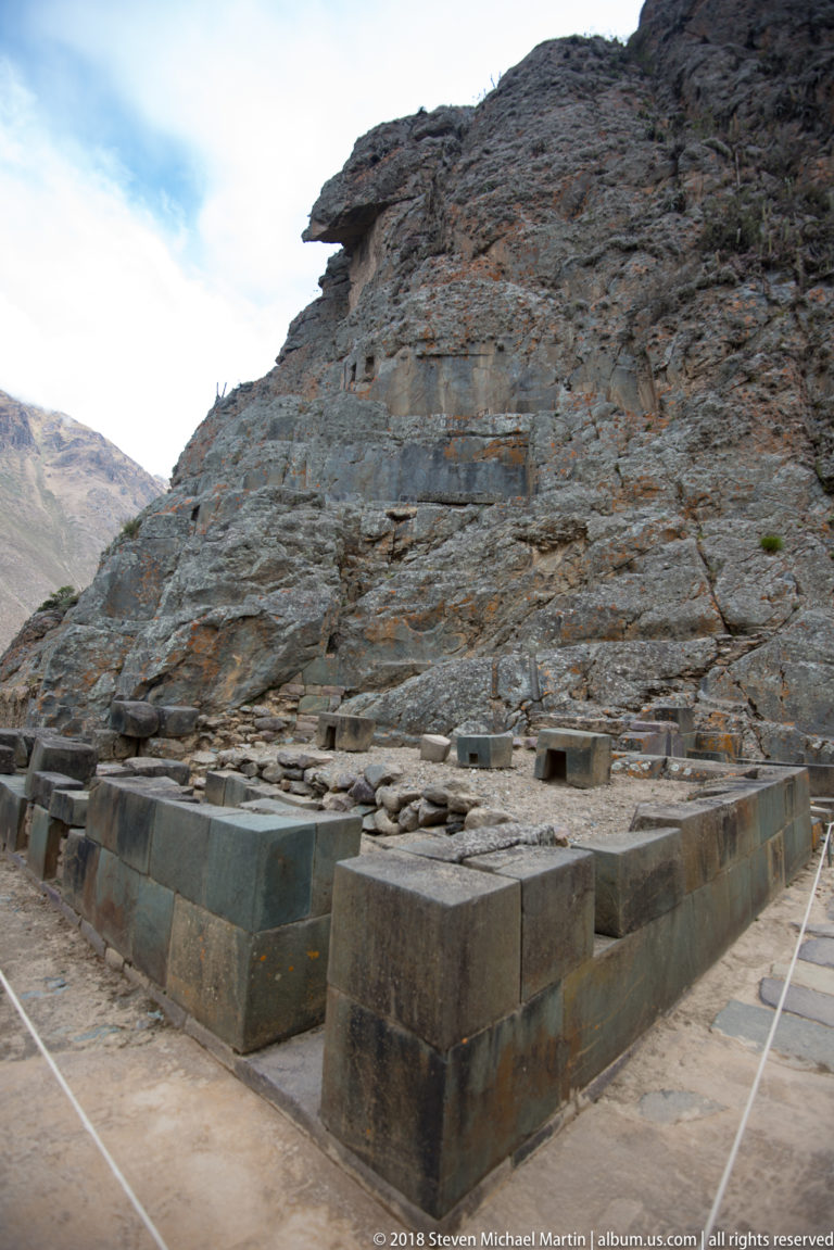 Worked rock face bordered by large squared stone blocks and lower masonry at Ollantaytambo.