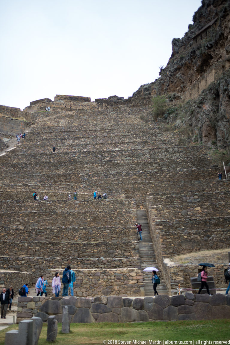 Large stone terraces at Ollantaytambo with a central staircase and visitors along the lower levels.