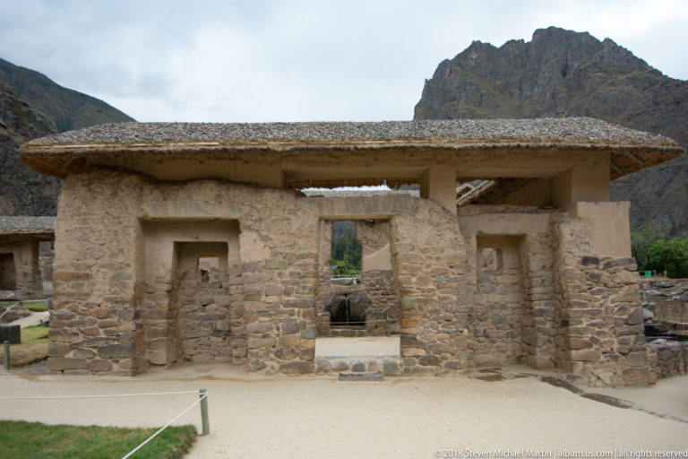 Front view of a roofed stone-and-earth structure with rectangular openings at Ollantaytambo.