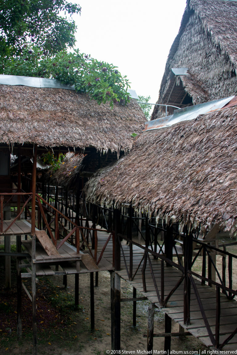 Overlapping palm-thatched roofs above intersecting raised wooden walkways and railings at Tuhauyo Lodge.
