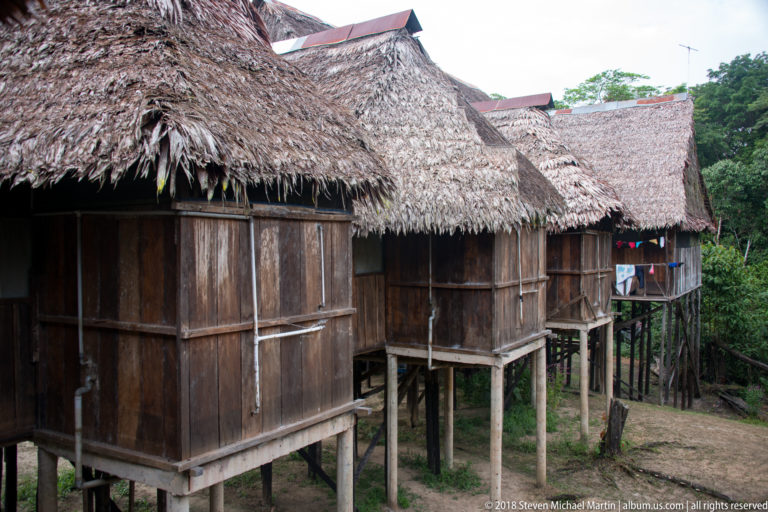 Row of wooden guest cabins raised on tall posts beneath steep palm-thatched roofs at Tuhauyo Lodge.