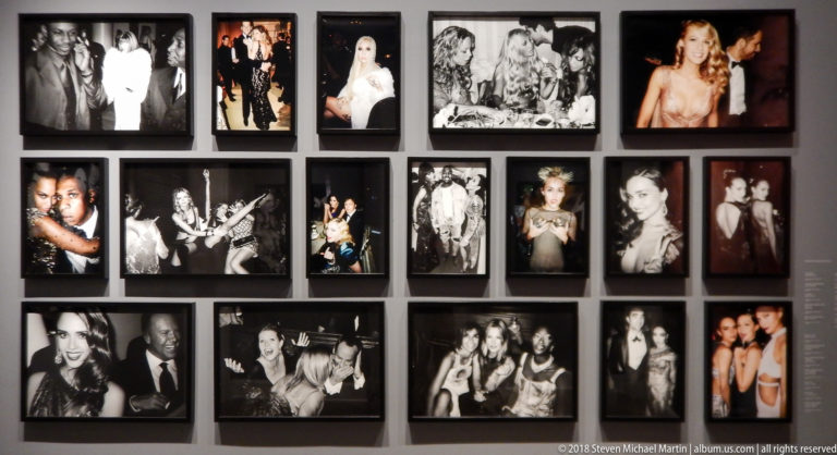 Gallery wall densely arranged with framed black-and-white and color portraits, fashion photographs, and event scenes.