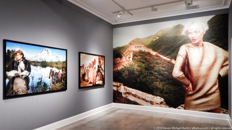 Gallery corner with multiple large fashion photographs, including mountain scenery and a wall-sized Great Wall image.