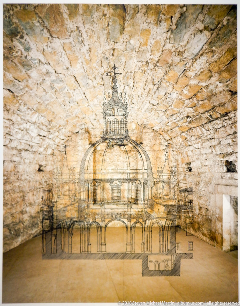 Linear drawing of a domed classical-style building spanning a rough stone-vaulted wall and floor.