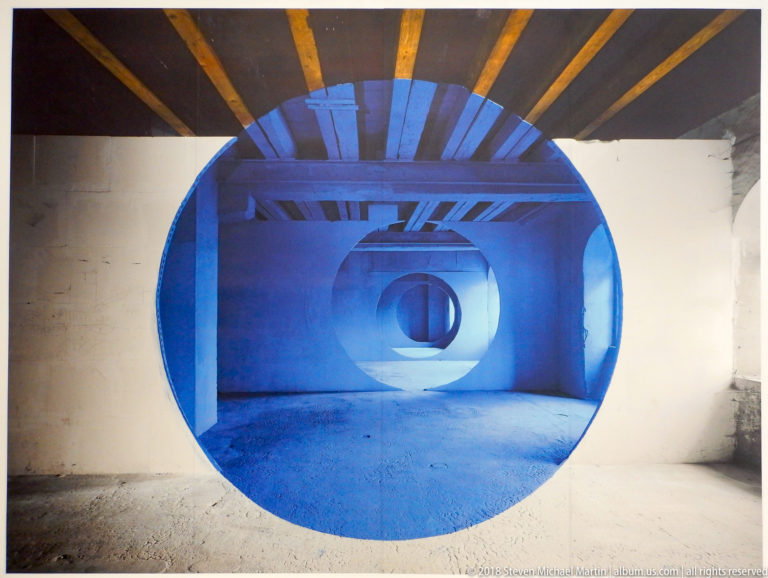 Large blue circular opening aligned with repeated concentric forms through several interior spaces.