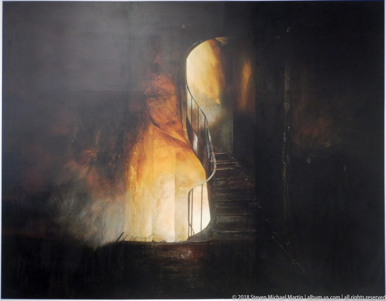 Narrow staircase rising through smoky amber light in a dark contemporary installation.