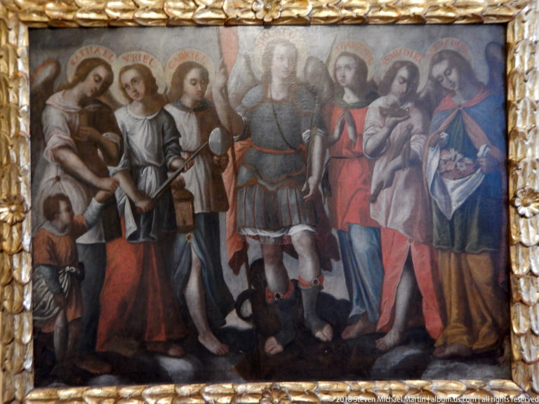 Framed religious painting with an armored central figure, surrounding sacred figures, inscriptions above heads, and a thick gilded frame.