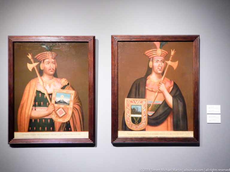 Two framed portraits of Indigenous Andean rulers wearing patterned garments and headgear and holding heraldic shields.