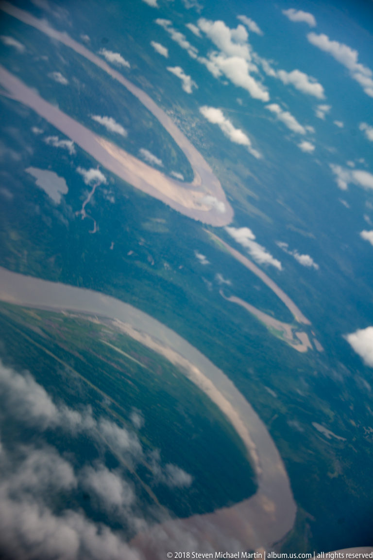 Aerial view of a broad winding river with sandbars, islands, and forested floodplain.
