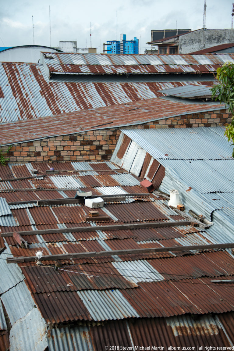 Patchwork of rusted brown and silver corrugated roofs seen from above in Iquitos.