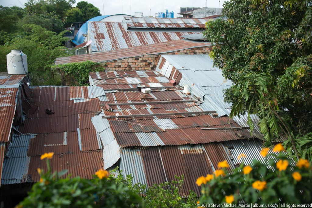 Elevated view across rusted and silver corrugated-metal rooftops in a dense Iquitos neighborhood.