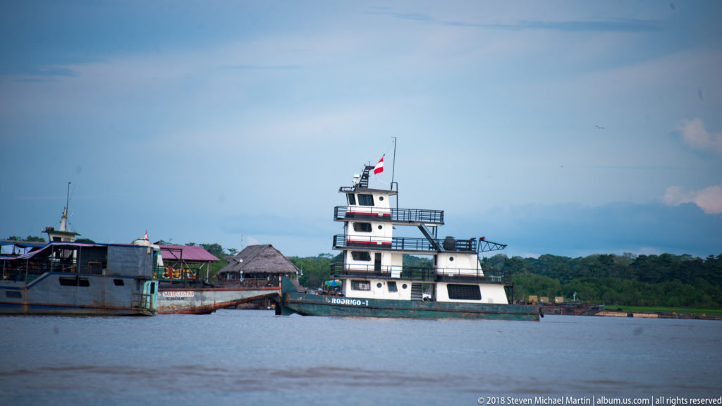 Compact multi-deck workboat with tall wheelhouse traveling on the river near Iquitos.