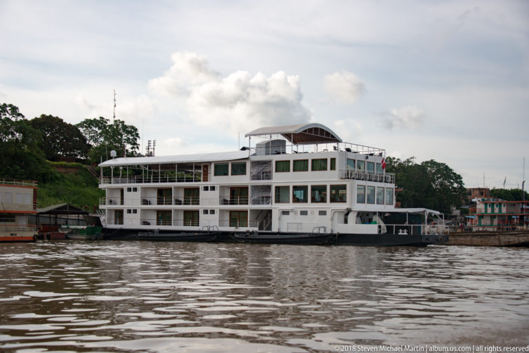 Large white multi-deck river vessel moored along the bank near Iquitos.