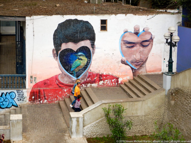 Large mural of two faces beside concrete steps, including a figure with a heart-shaped scene across the face.