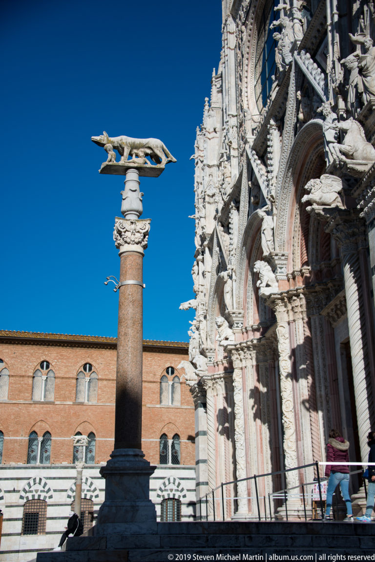 An elongated stone animal projects from the cathedral wall above smaller carved figures.