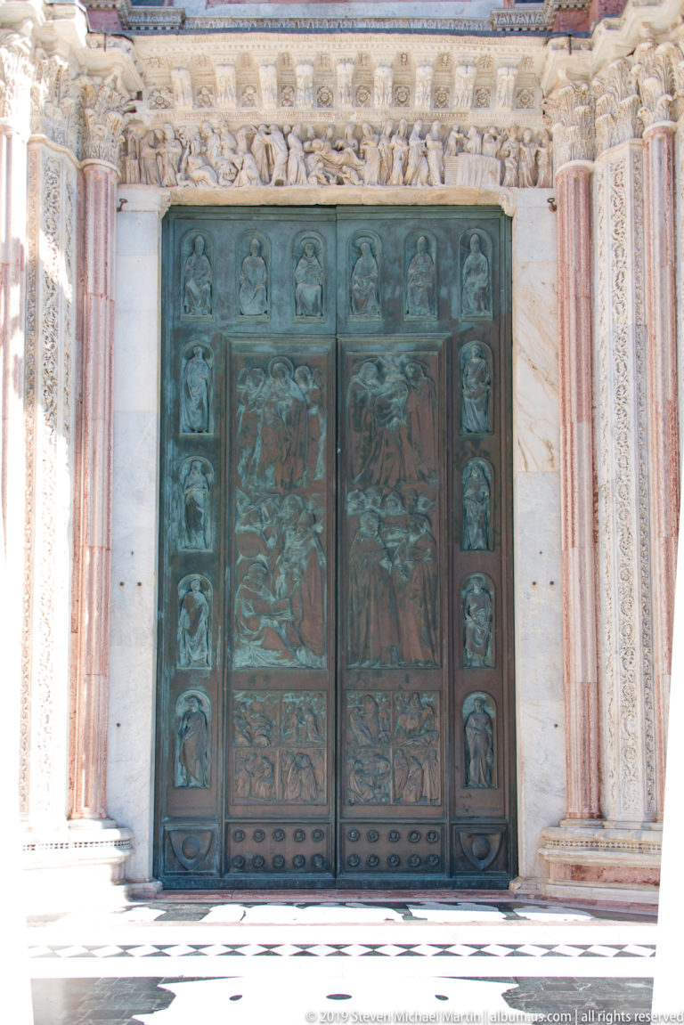 Standing stone figures line a recessed niche in the cathedral’s marble façade.