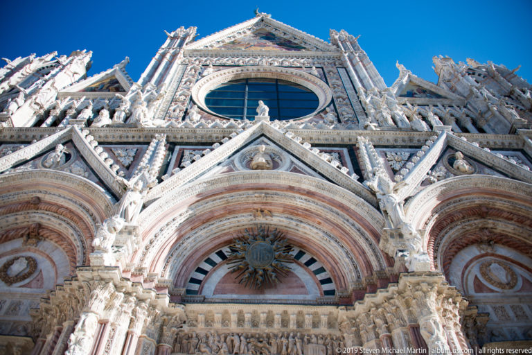 Siena Cathedral’s oval window and sculpted gables rise above the central portal.