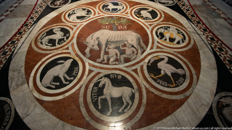 A marble roundel with the she-wolf and twins is surrounded by labeled animal medallions.