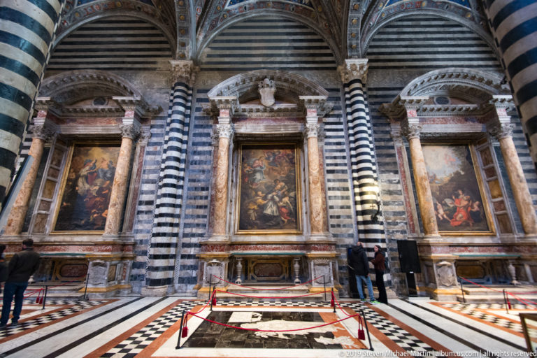 Striped piers divide side chapels with framed paintings beneath the high cathedral vault.