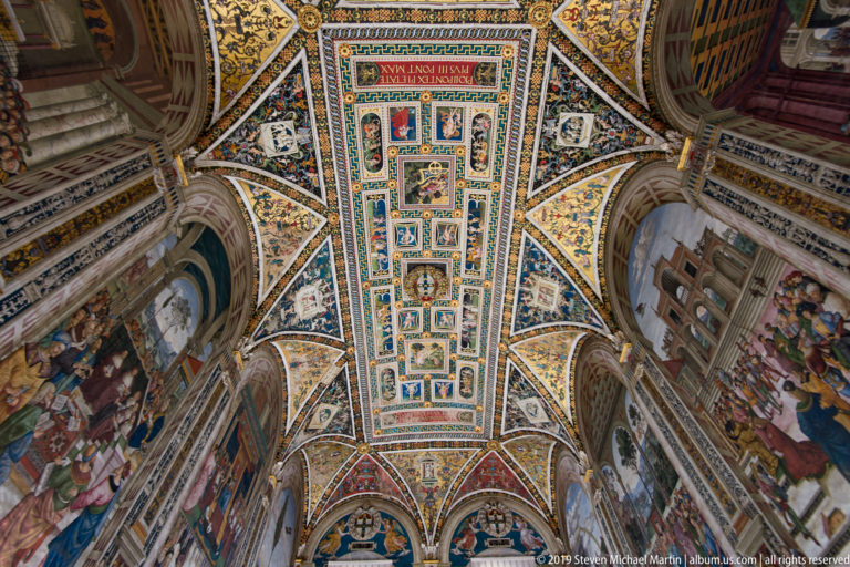 A narrow central panel of framed scenes is surrounded by colorful geometric vault decoration.