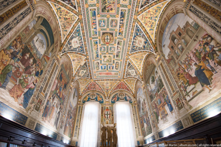 A long interior view along the nave toward painted vaults above the marble pavement.